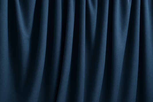 Rideaux occultants bleu foncé légèrement froissés, suspendus en plis souples, illustrant leur texture épaisse et leur tombé naturel dans un intérieur sobre.