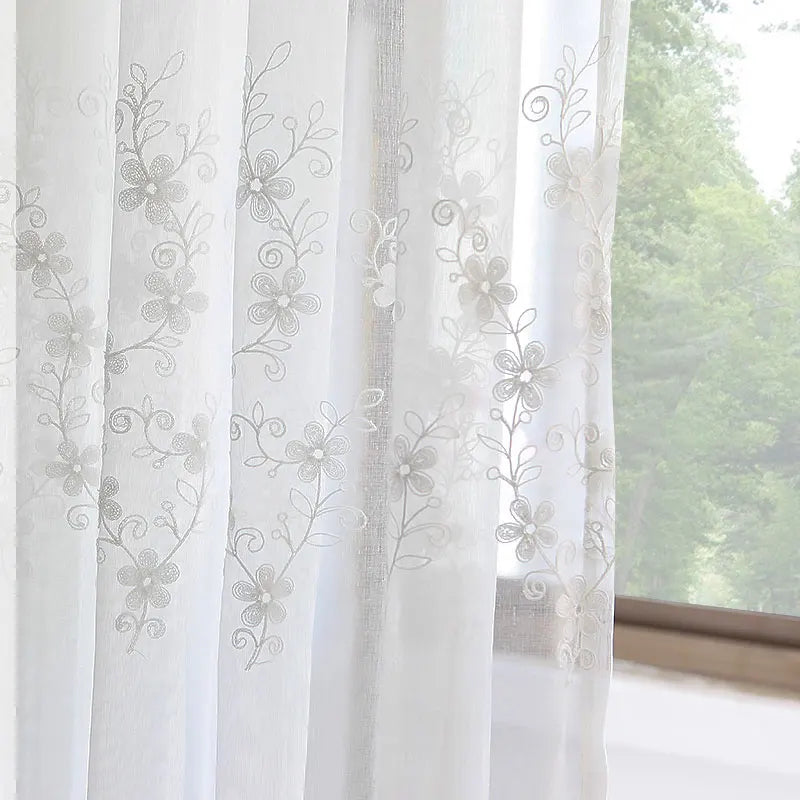 Voilage blanc brodé avec motifs floraux délicats en gros plan