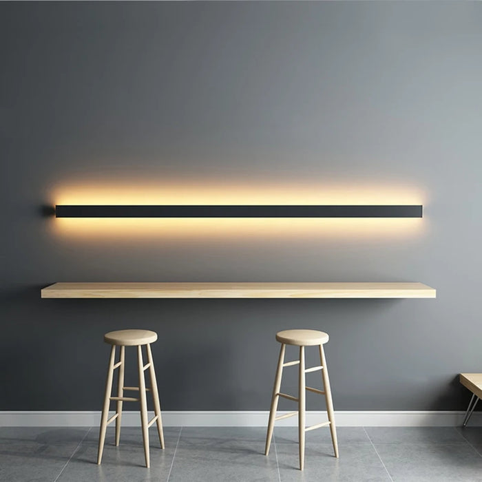 Applique murale longue minimaliste noire avec lumière douce dans une chambre moderne