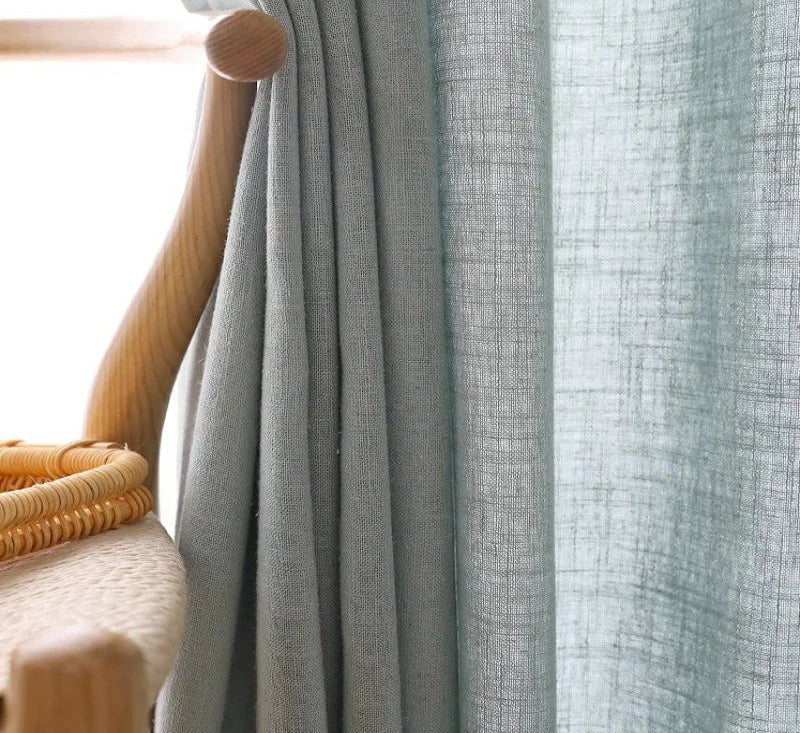 Voilage en tulle gris clair posé près d’un vase décoratif, apportant une lumière douce et naturelle à la pièce.