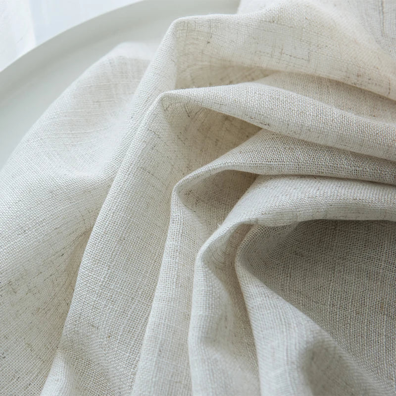 Vue rapprochée d’un tissu de voilage beige effet lin naturel, délicatement froissé, mettant en valeur sa texture douce et sa transparence.