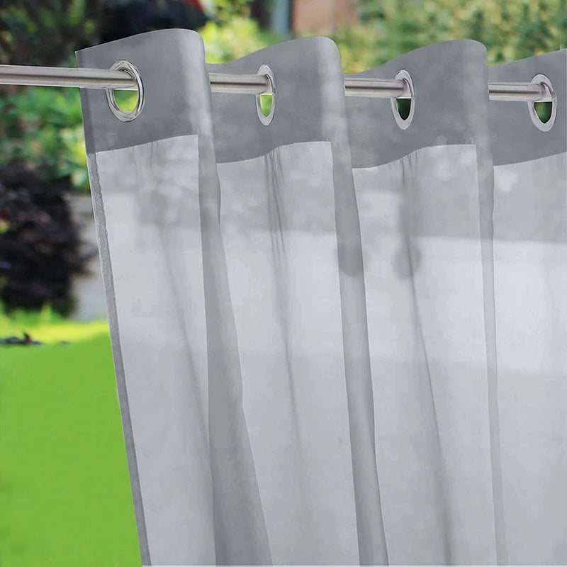 Voilage gris extérieur avec œillets métalliques pour une fixation solide sur une tringle de jardin.