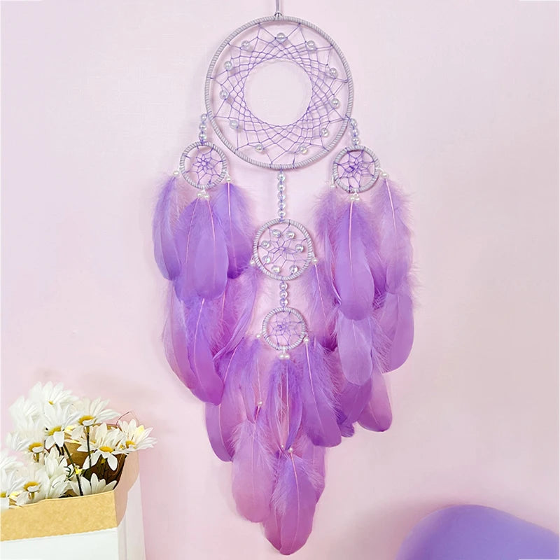 Un magnifique attrape-rêves violet suspendu, orné de plumes légères et de motifs délicats, créant une atmosphère apaisante et relaxante.