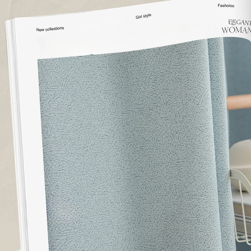 Zoom sur le tissu du rideau gris tendance mis en avant dans un catalogue, illustrant la finesse de sa texture et son tombé naturel.