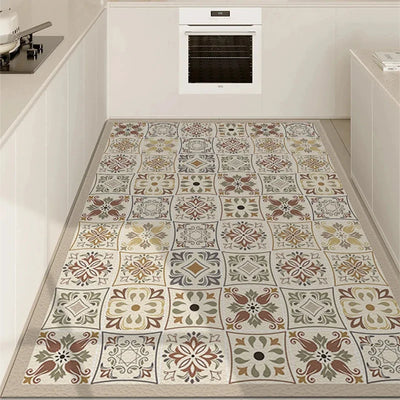 Le carrelage au sol de cette cuisine présente un motif ornemental floral élégant et coloré, créant un beau contraste avec les éléments en blanc de la pièce.