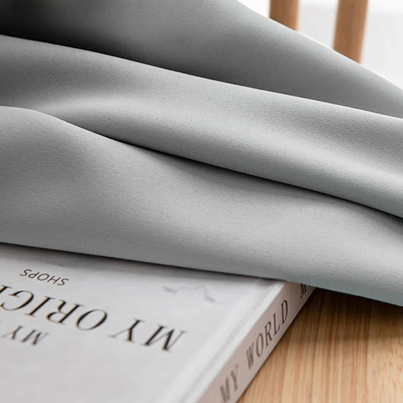 Drapé élégant de couleur grise posé délicatement sur un livre au design moderne et épuré, idéal pour ajouter une touche de sophistication à votre intérieur.