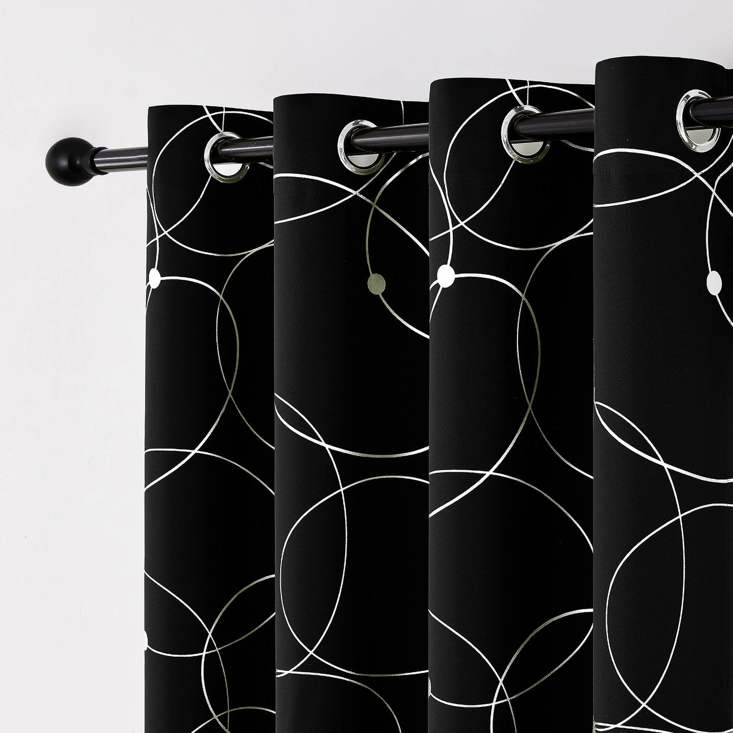 Zoom sur les œillets métalliques d’un rideau noir décoré de cercles blancs graphiques.