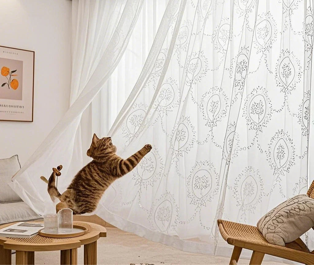 Voilage blanc esprit bord de mer avec motif floral et chat en mouvement dans un salon lumineux