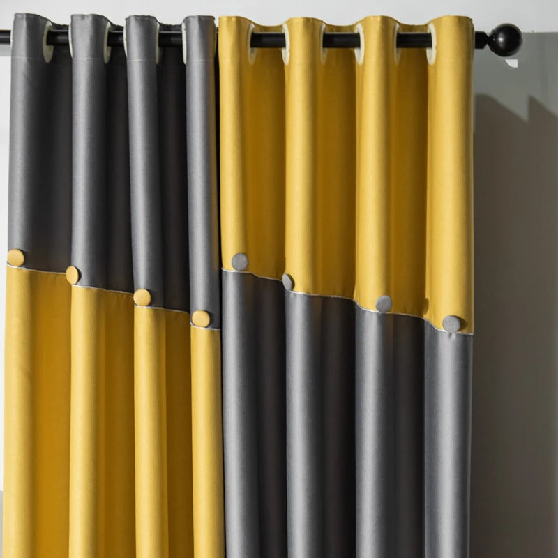 Gros plan sur les plis des rideaux bicolores jaune moutarde et gris, avec œillets métalliques pour une finition contemporaine.