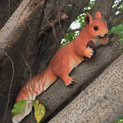 Statue écureuil gris foncé suspendu à un arbre dans un jardin