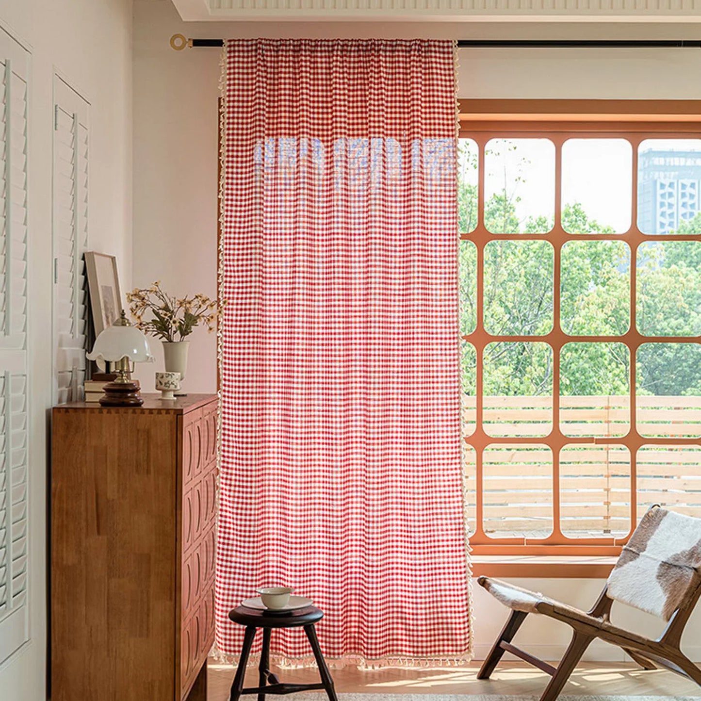 Rideau à carreaux rouge et blanc dans un salon lumineux avec de grandes fenêtres, offrant une ambiance chaleureuse et accueillante. Idéal pour ajouter une touche de style rétro à votre intérieur et compléter la décoration de votre pièce. Parfait pour un salon, une chambre ou un espace détente.