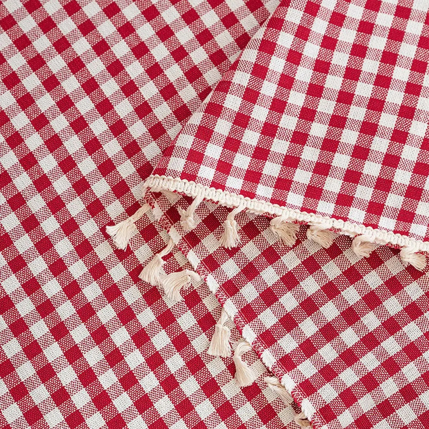 Nappe à carreaux rouges et blancs avec franges décoratives pour une table élégante et champêtre. Design classique idéal pour les repas en extérieur ou les occasions spéciales.
