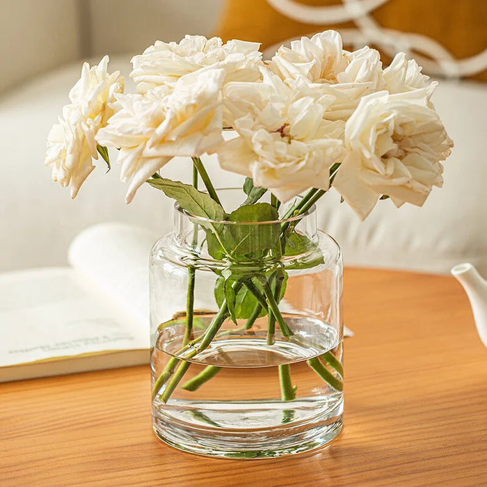 Grand vase en verre transparent sur table basse de salon avec fleurs