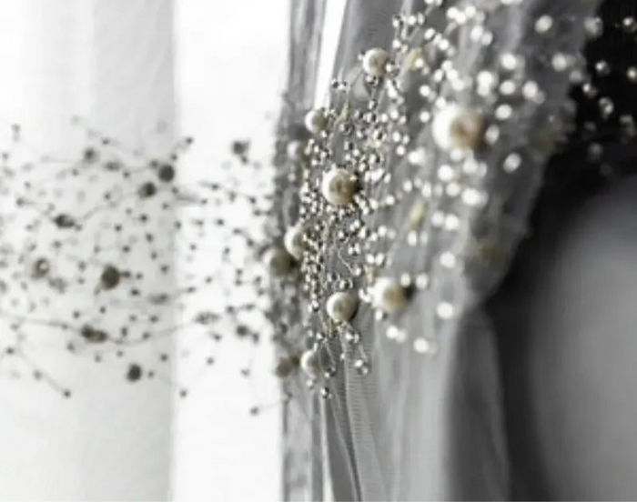 Voilage transparent gris perle décoré de perles blanches élégantes.