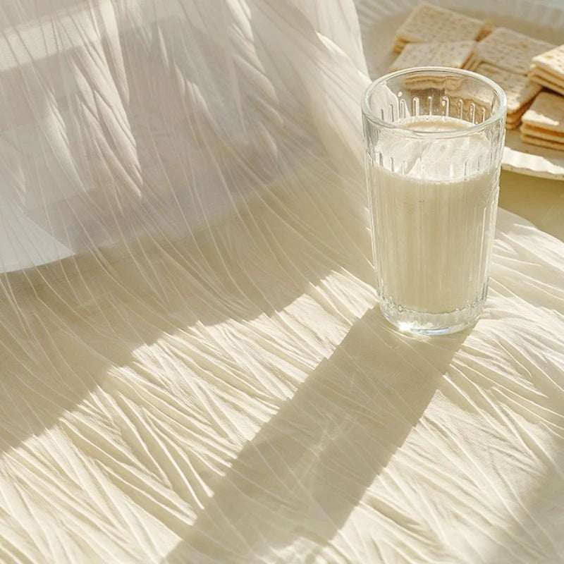 Verre de lait sur une table recouverte du voilage blanc froissé laissant passer la lumière du matin.