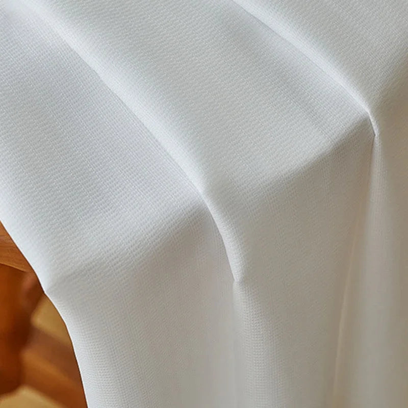 Gros plan sur la texture fluide et légèrement texturée du voilage blanc en polyester