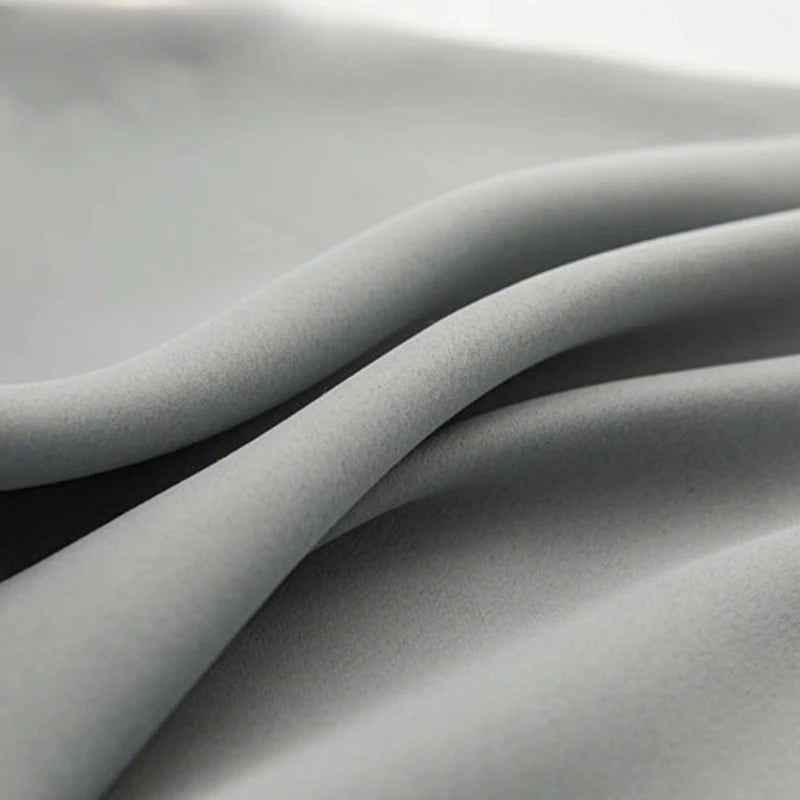 Drapé élégant et ondulé d'un tissu gris, idéal pour ajouter une touche de sophistication à toute décoration intérieure. Parfait pour confectionner des rideaux modernes ou des housses de coussins raffinés.