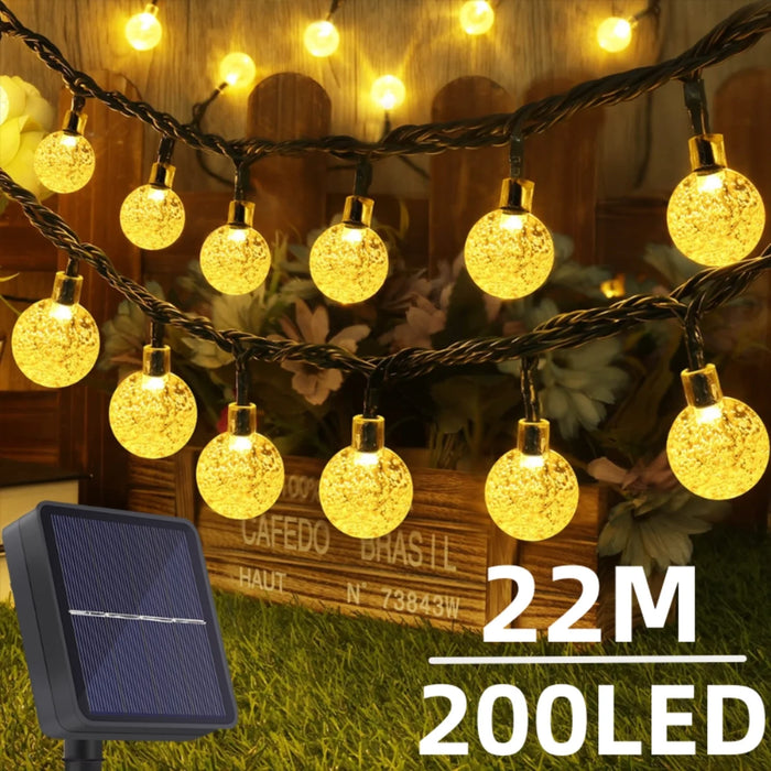 Guirlande solaire extérieure 200 LED avec globes en cristal illuminant un jardin