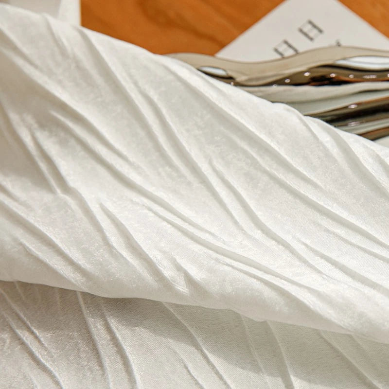 Gros plan sur le tissu froissé du voilage blanc, mettant en valeur ses plis naturels et sa texture douce.