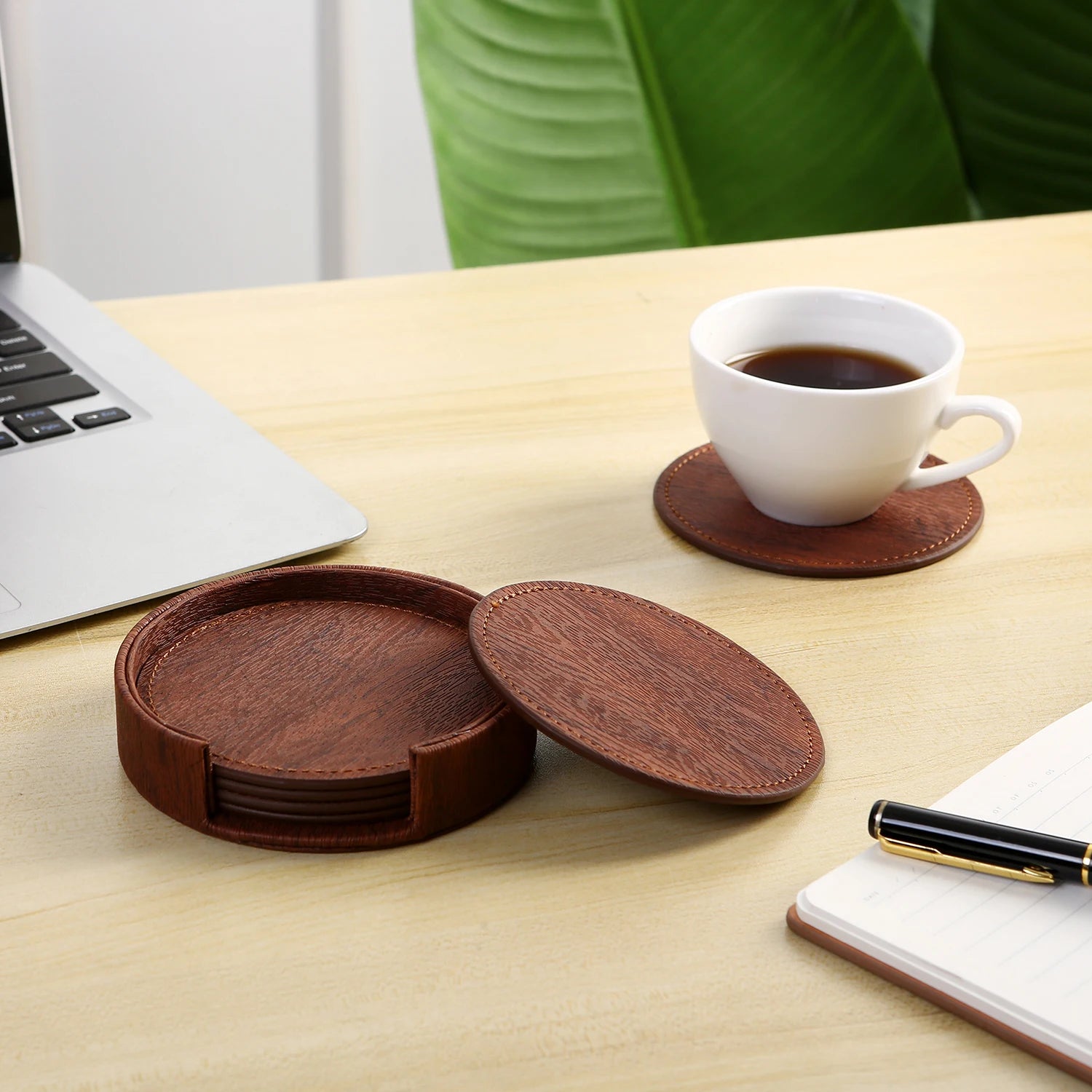 Sous-verres ronds en bois foncé sur le bureau, avec un ordinateur portable et une tasse de café.