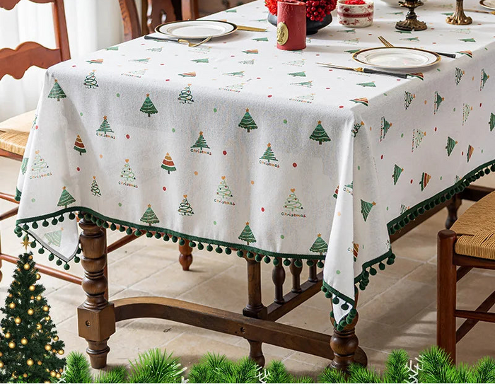 Une nappe de table décorative avec un motif de sapins de Noël et de pompons colorés, créant une atmosphère festive pour la période des fêtes.