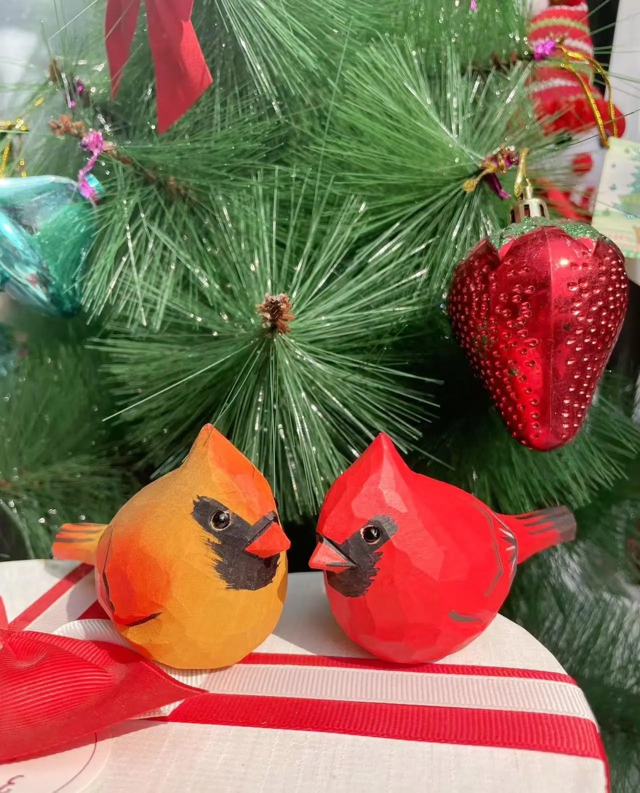 Des ornements d'oiseau rouges et oranges ornent un sapin de Noël garni de décorations rouges et vertes.