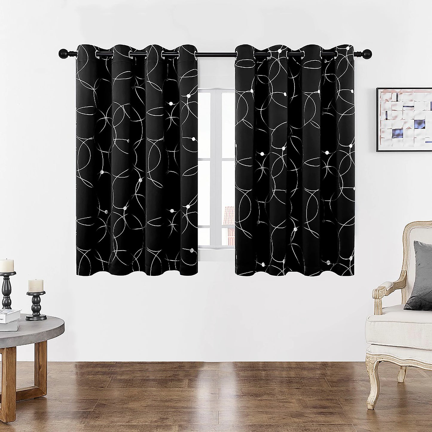 Gros plan sur la finition haute d’un rideau noir à motifs géométriques blancs avec œillets.