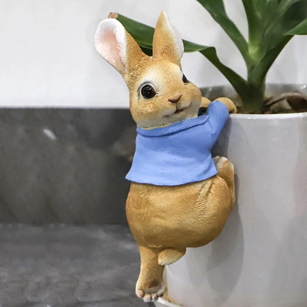 Lapin doré mignon avec un bandana bleu autour du cou, posé près d'une plante en pot.