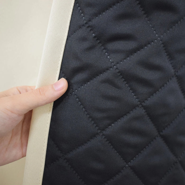 Gros plan d'une main tenant un produit avec un motif matelassé noir et des bordures claires. Le design en losanges géométriques évoque une finition élégante et moderne, idéal pour une décoration intérieure sophistiquée. L'image met en valeur la qualité et le souci du détail.