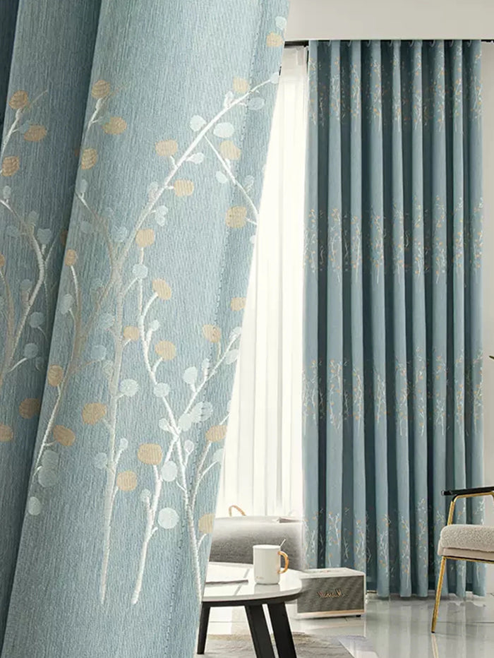 Des rideaux de design d'intérieur en textile bleu luxueux avec un motif floral, suspendus comme une solution de traitement de fenêtre dans un salon bien aménagé. La pièce contient également des éléments de décoration comme une lampe moderne, un pot de fleurs avec une belle plante d'intérieur sur un papier peint élégant. Une idée parfaite de revêtement de fenêtre pour améliorer l'esthétique de votre espace de vie.