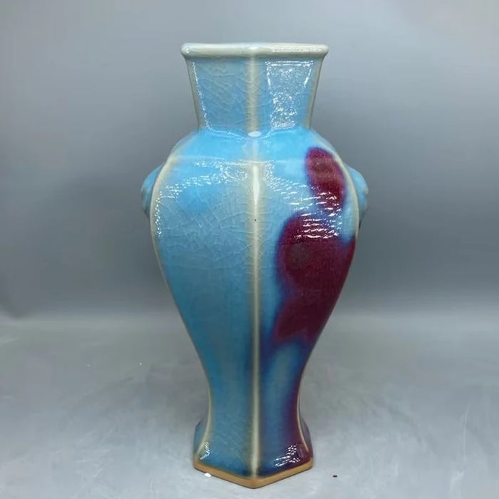 Vase hexagonal en verre bleu et rouge aux motifs ondulés et brillants.