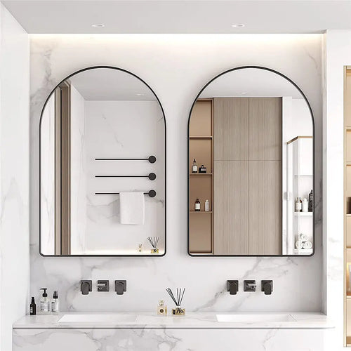 Un intérieur de salle de bain moderne et épuré avec deux miroirs encadrés de métal noir, des étagères encastrées et une vasque blanche posée sur un plan de travail en marbre.