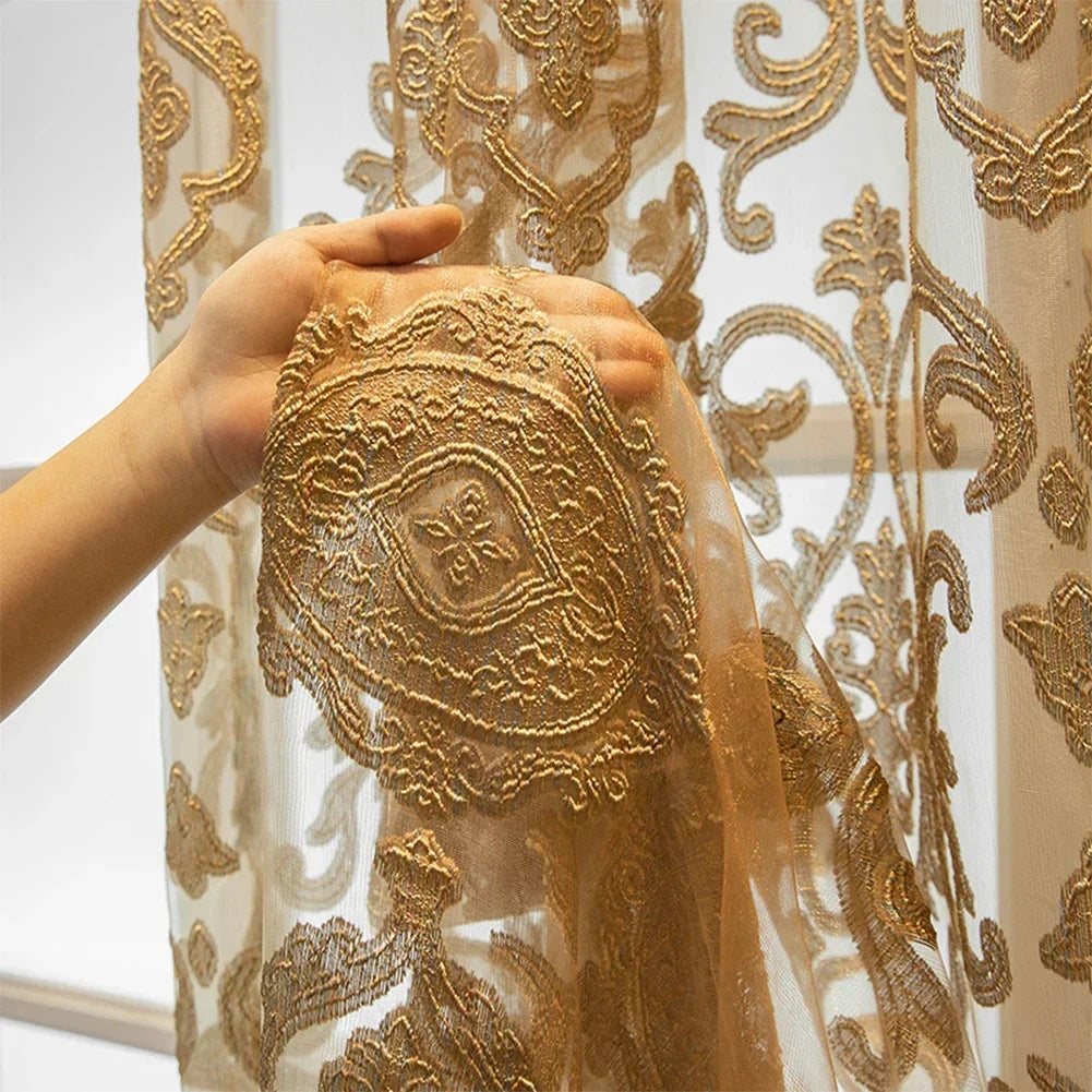 Vue complète d’un voilage doré brodé au design oriental richement décoré, installé dans un intérieur lumineux avec murs crème et lampe dorée.