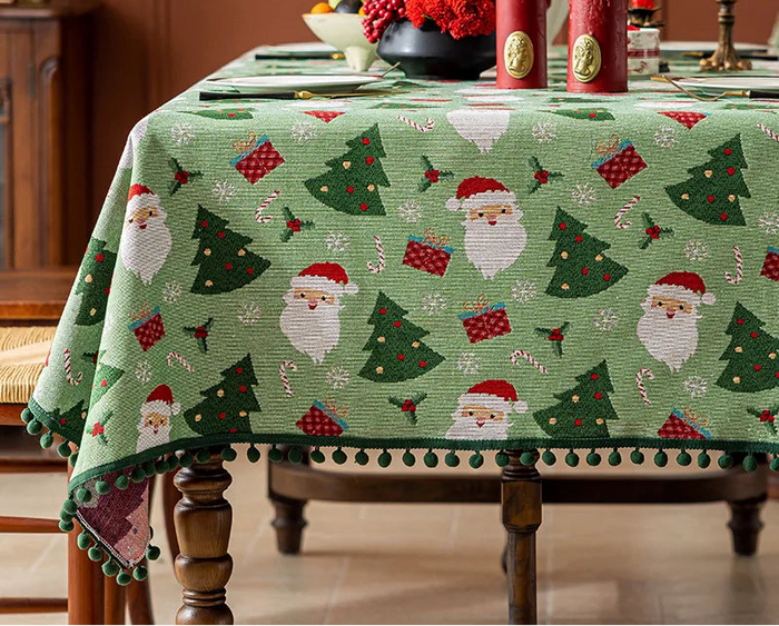 Cette image présente une belle nappe de table festive aux motifs de Noël, avec des sapins, des Pères Noël et des décorations rouges et vertes, créant une atmosphère chaleureuse et joyeuse pour les fêtes.