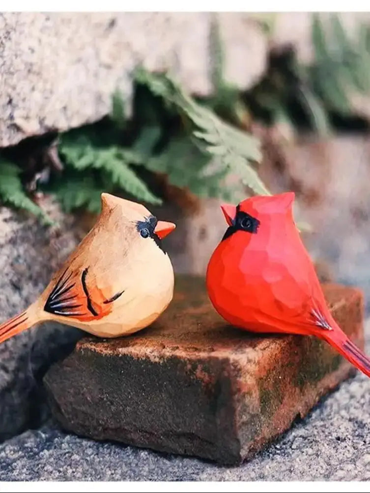 Deux cardinaux rouges perchés sur une souche de bois, avec des feuillages verts en arrière-plan, créant une scène colorée et naturelle.