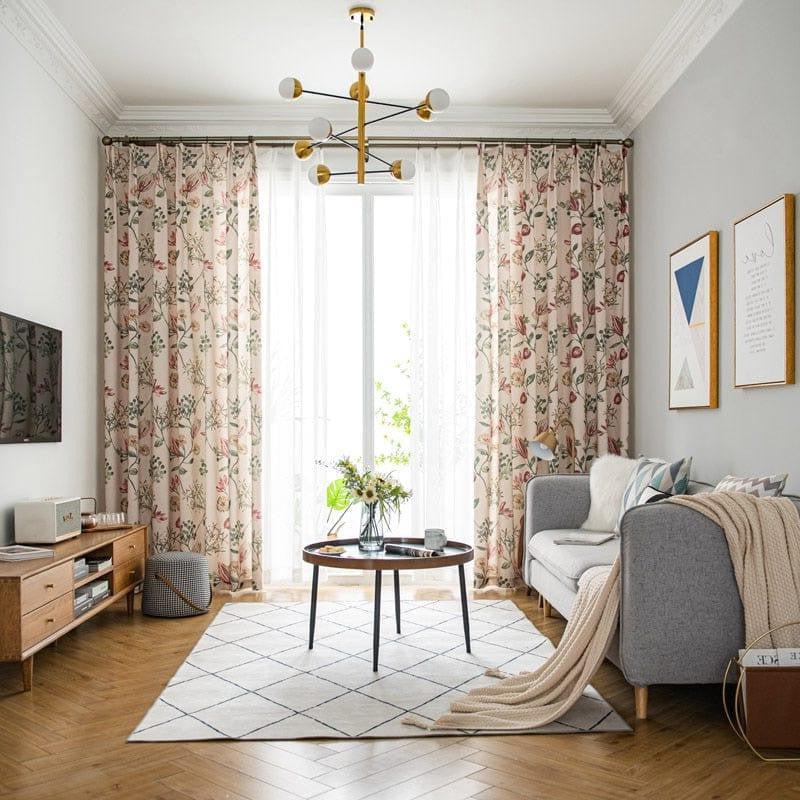 Salon moderne avec rideaux à motifs floraux, canapé gris et table basse design sur un tapis géométrique. Ambiance élégante avec décoration murale contemporaine et luminaires stylés. Intérieur lumineux et accueillant.