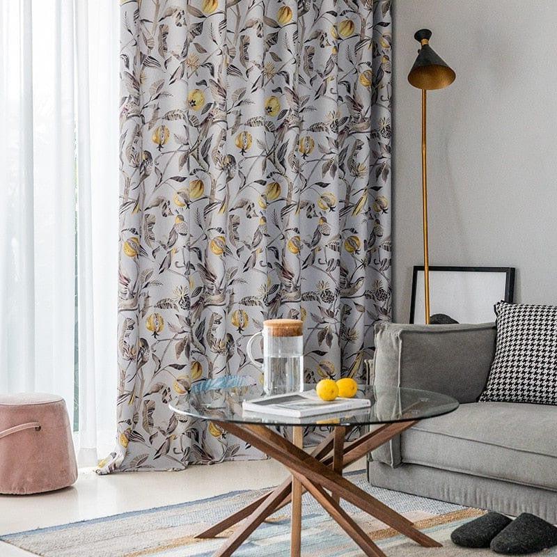 Décoration intérieure moderne avec rideaux à motif floral, lampe élégante et table basse en verre sur un tapis coloré, créant une ambiance chic et confortable. Parfaite intégration dans un salon accueillant, avec un canapé assorti et des touches de couleur. Parfaite pour apporter une touche de nature dans votre espace de vie.