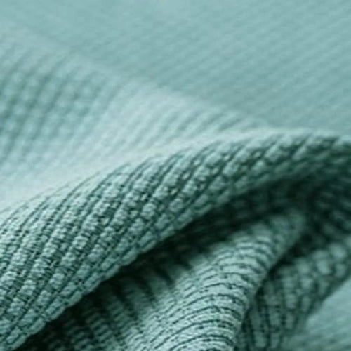 Texture de tissu vert clair, gros plan sur un tissu plissé aux motifs en relief, idéal pour accessoires de maison ou vêtements, design tendance et moderne.