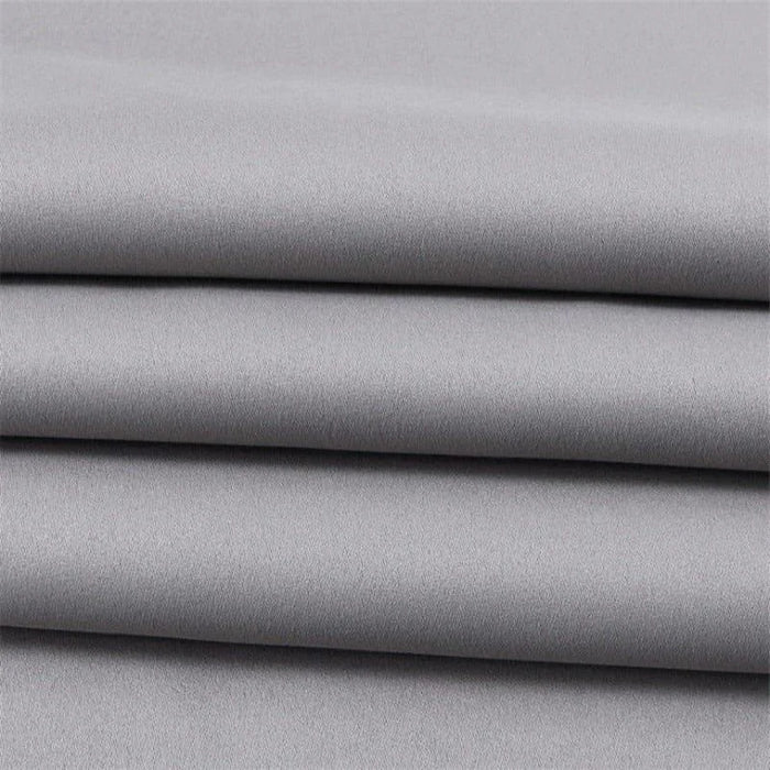 Tissu gris élégant, plié en couches, idéal pour la confection de vêtements sur mesure ou projets de décoration intérieure, offrant un style moderne et intemporel.