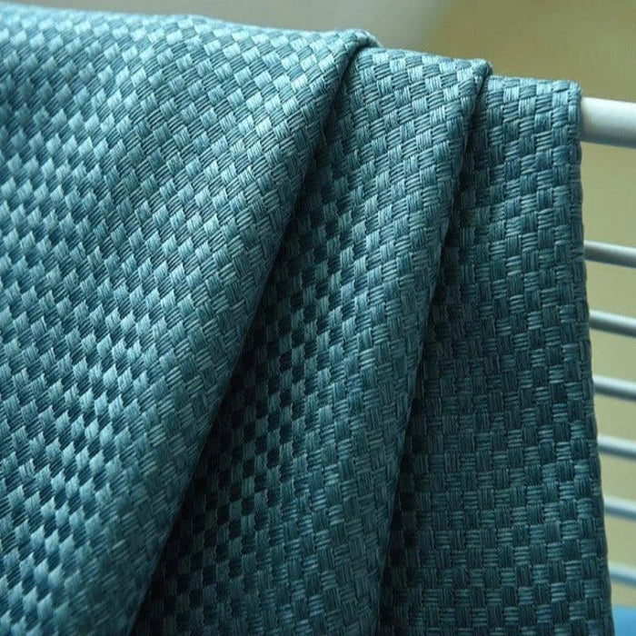 Image d'un tissu bleu texturé avec un motif à carreaux, idéal pour la décoration intérieure et l'ameublement. Ce textile de haute qualité présente un design élégant et contemporain, parfait pour ajouter une touche de sophistication à tout espace de vie.
