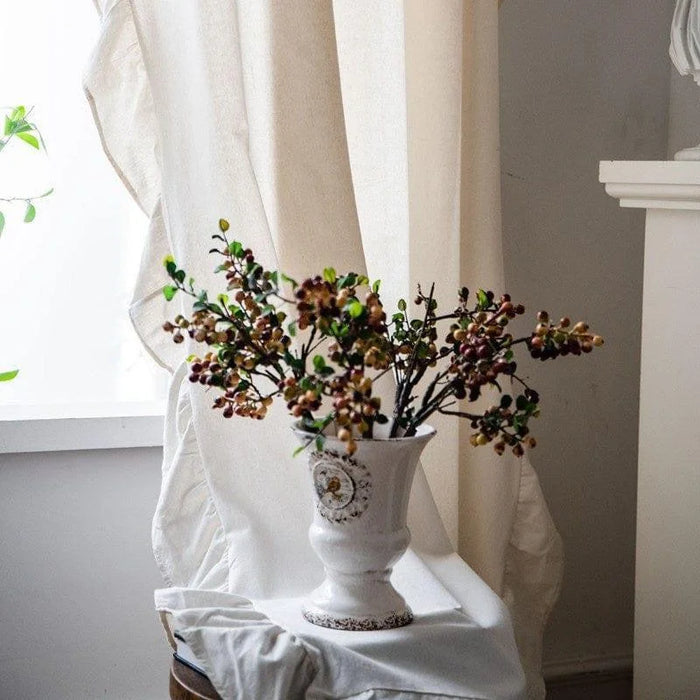 Vase décoratif élégant placé sur une table dans un salon lumineux. Ce vase classique, orné de détails raffinés, est mis en valeur par un arrangement floral aux tons automnaux. Parfait pour ajouter une touche de charme et de sophistication à votre intérieur. Idéal pour décorer un coin cosy ou une étagère.