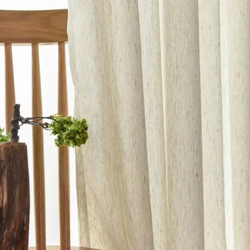 Chaises en bois élégantes avec rideaux légers pour une ambiance naturelle et apaisante dans le salon. Décoration sobre intégrant un vase original, idéal pour un intérieur moderne et chaleureux.