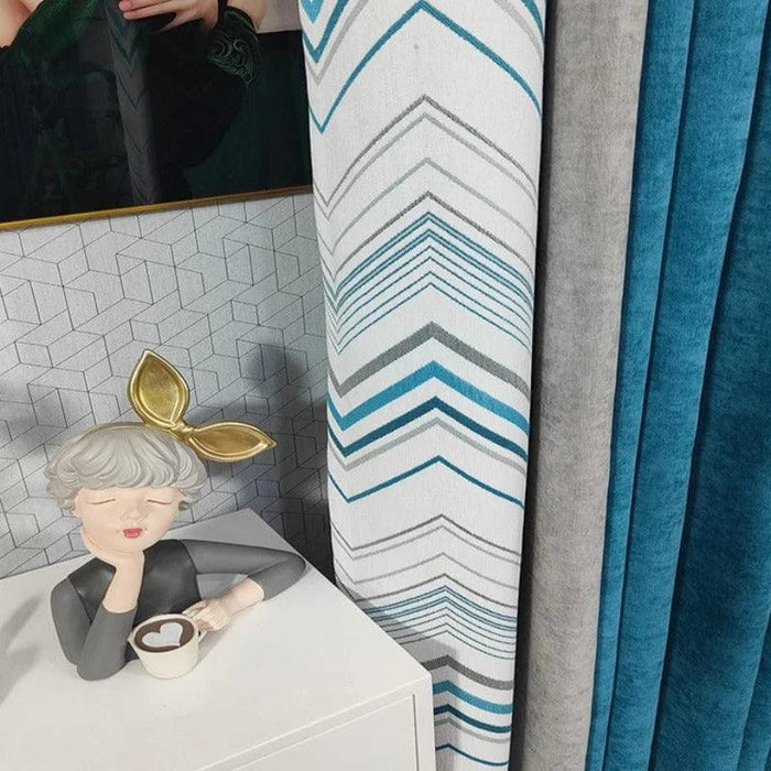 Rideaux modernes avec motifs géométriques bleu et gris, parfaits pour un salon contemporain. Design élégant avec statue décorative et tasse sur table blanche. Idéal pour rehausser la décoration intérieure et ajouter une touche de couleur et de style.
