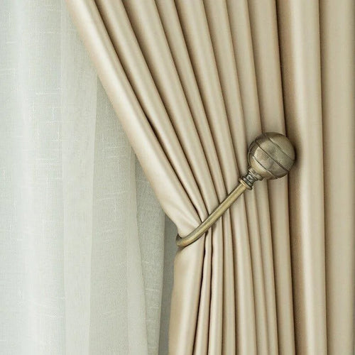 Rideau élégant beige attaché par un embrasse métallique, offrant une décoration raffinée et une lumière tamisée dans la pièce. Design moderne et chic parfait pour une ambiance cosy et contemporaine. Accessoire idéal pour ajouter une touche de sophistication à votre intérieur.