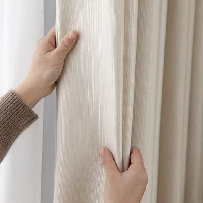 Rideau beige élégant avec mains ajustant le tissu, idéal pour ajouter une touche de sophistication à votre intérieur.