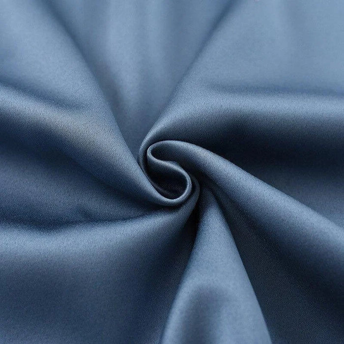 Texture de tissu bleu uni avec un effet satiné et un agencement en pli élégant, idéal pour les vêtements ou la décoration intérieure. Évoque un style raffiné et moderne.