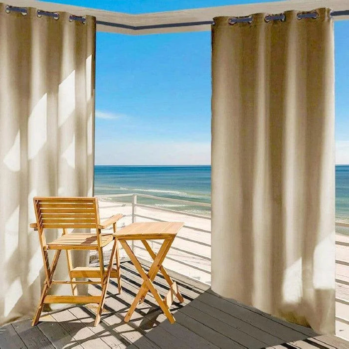 Rideau beige pour extérieur avec oeillets sur terrasse en bord de mer, créant un espace ombragé et intime; idéal pour balcons ou patios ensoleillés.