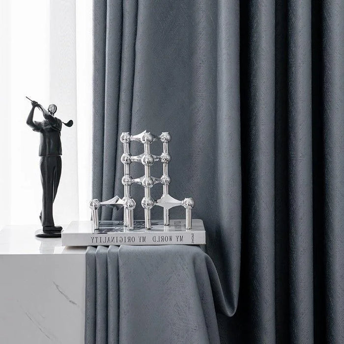 Rideaux élégants de couleur grise, parfaits pour ajouter une touche moderne et sophistiquée à votre intérieur. Accessoirisés avec une sculpture décorative et un livre posé sur une table, ces rideaux créent une ambiance chic et contemporaine dans n'importe quelle pièce de la maison.