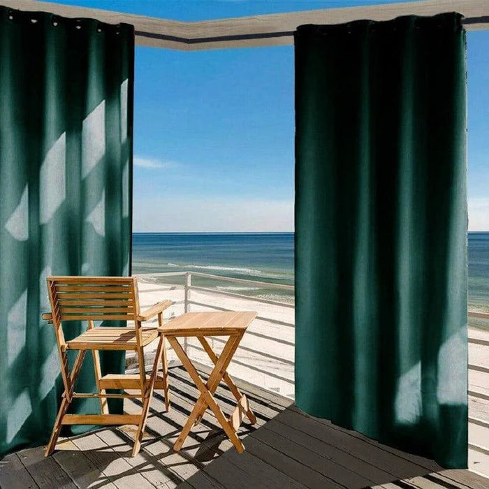 Chaises de jardin et table pliable en bois sur une terrasse avec vue sur la mer, entourées de rideaux épais, idéal pour créer un espace extérieur ombragé et relaxant.