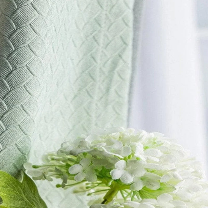 Rideau vert clair avec motif tressé en relief, accompagné de fleurs blanches délicates. Idéal pour ajouter une touche de sérénité et d'élégance à votre intérieur. Parfait pour le salon, la chambre ou tout autre espace de vie nécessitant une ambiance apaisante.
